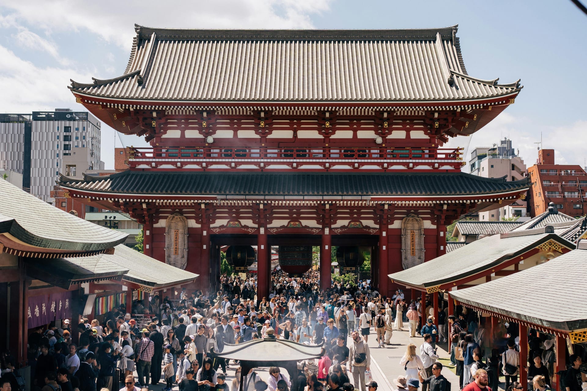 Wide view of Hozomon Gate at Senso-ji with large crowds gathered in the courtyard and incense burners in the foreground